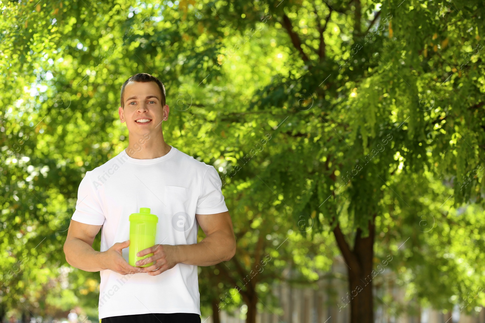 Photo of Athletic young man with protein shake at green park