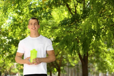 Athletic young man with protein shake at green park