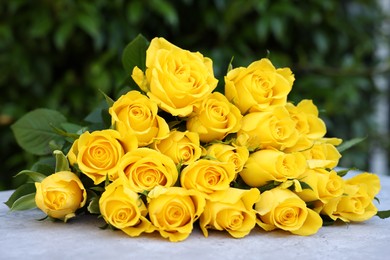 Beautiful bouquet of yellow roses on light table outdoors, closeup