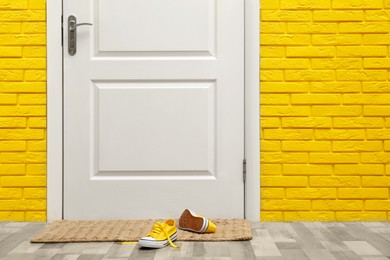 Photo of Stylish shoes on door mat in hallway
