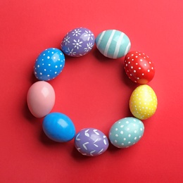 Frame made of painted Easter eggs on color background, top view. Space for text