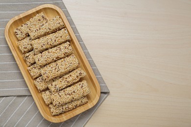 Plate with tasty sesame seed bars on wooden table, top view. Space for text