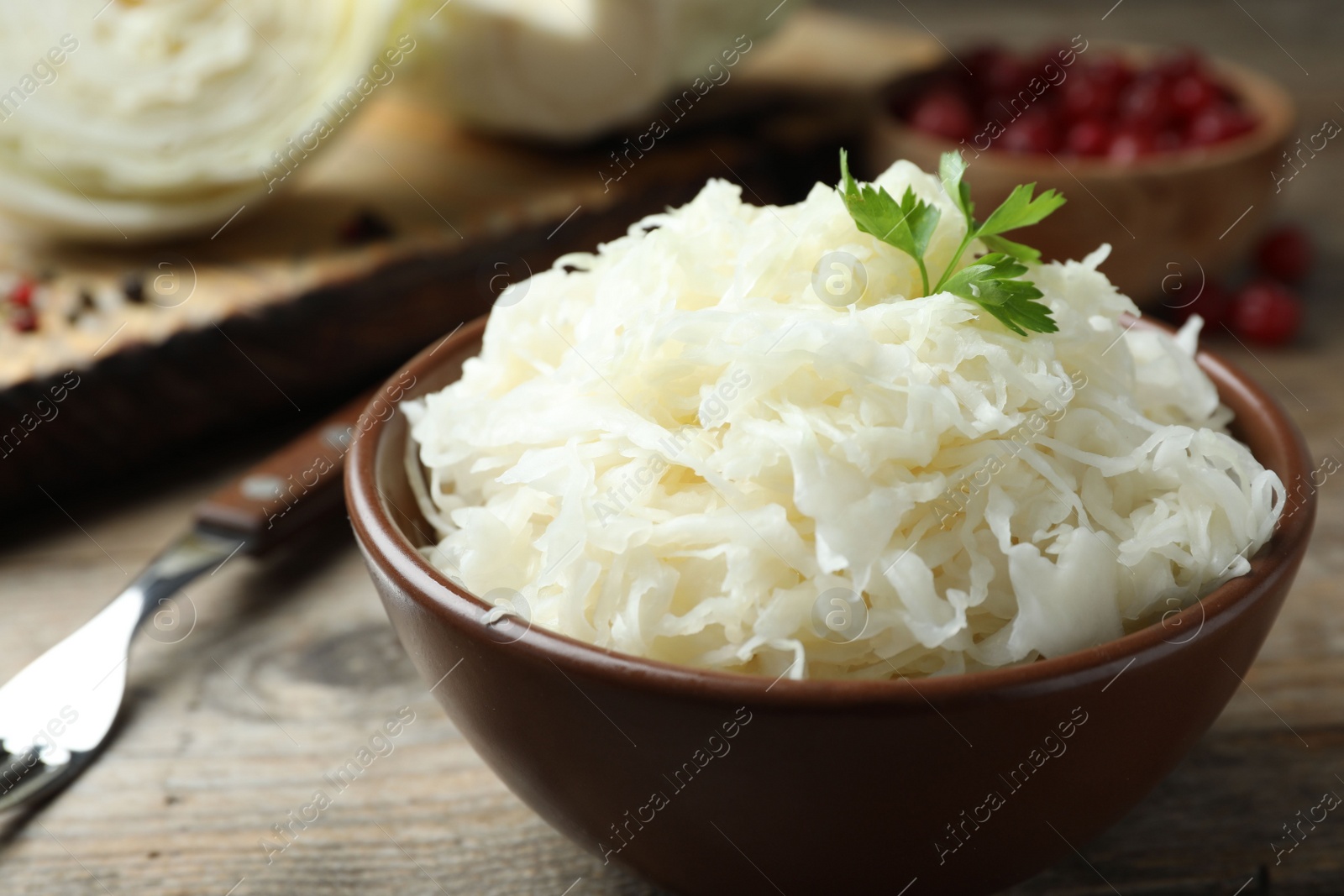 Photo of Tasty fermented cabbage on wooden table, closeup