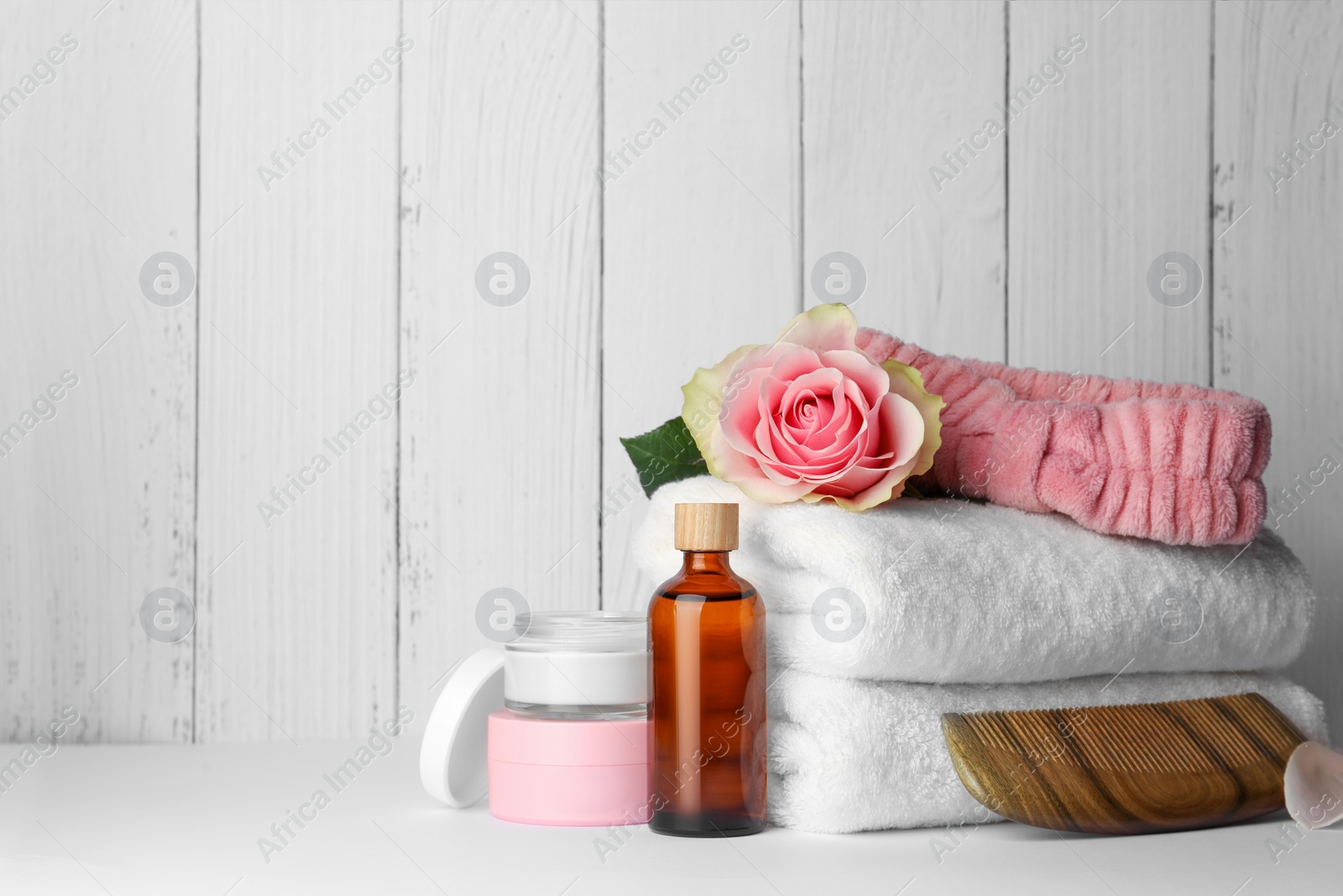 Photo of Composition with different spa products and rose on white table against wooden background. Space for text