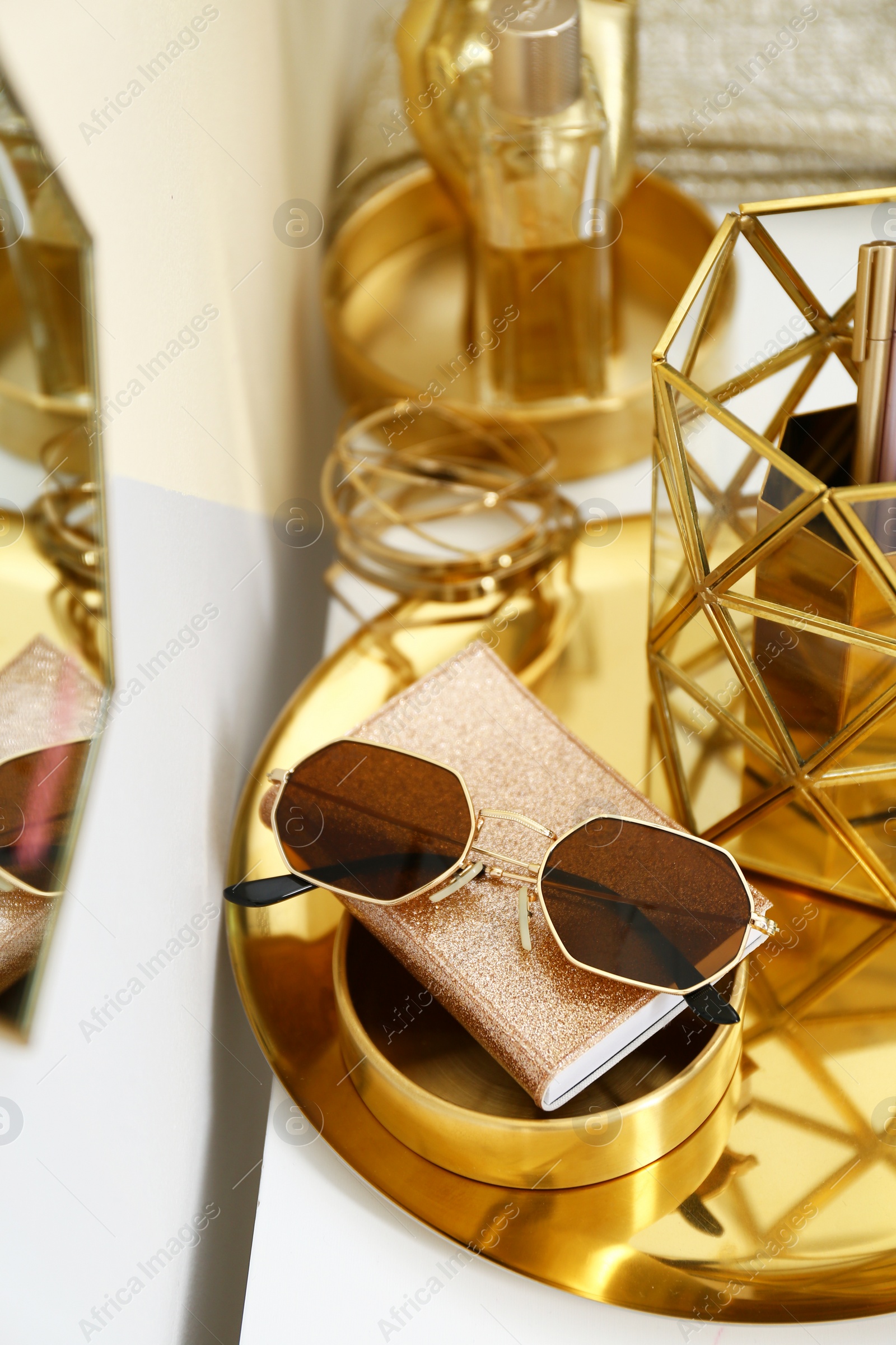 Photo of Gold tray with notebook, glasses and accessories on dressing table