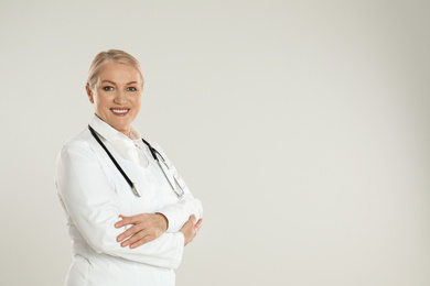 Photo of Portrait of mature doctor with stethoscope on light grey background. Space for text