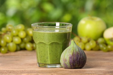Photo of Glass of fresh green smoothie and ingredients on wooden table outdoors
