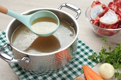 Photo of Delicious homemade bone broth and ingredients on wooden table