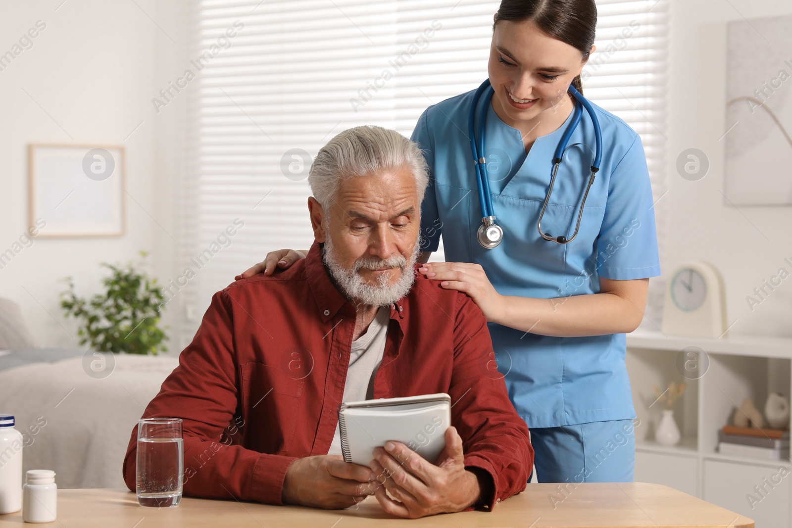 Photo of Young healthcare worker consulting senior man at wooden table indoors