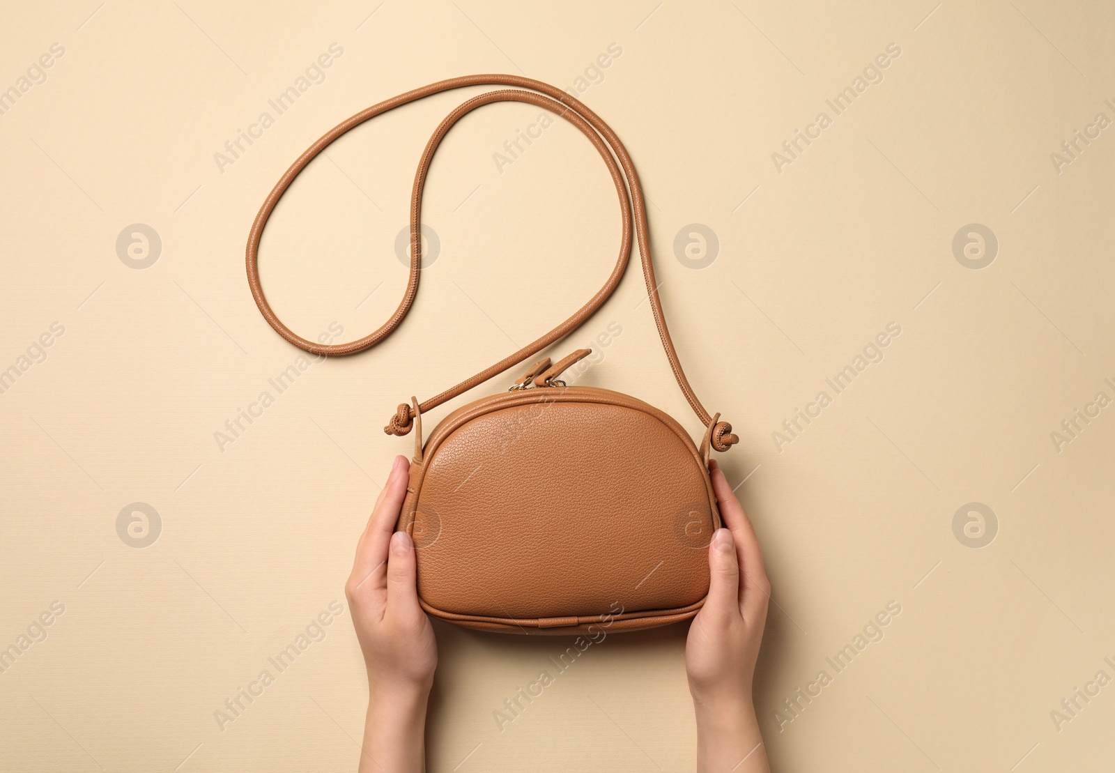 Photo of Woman with stylish bag on beige background, top view