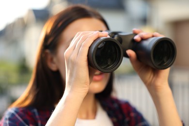 Photo of Concept of private life. Curious young woman with binoculars spying on neighbours outdoors, closeup