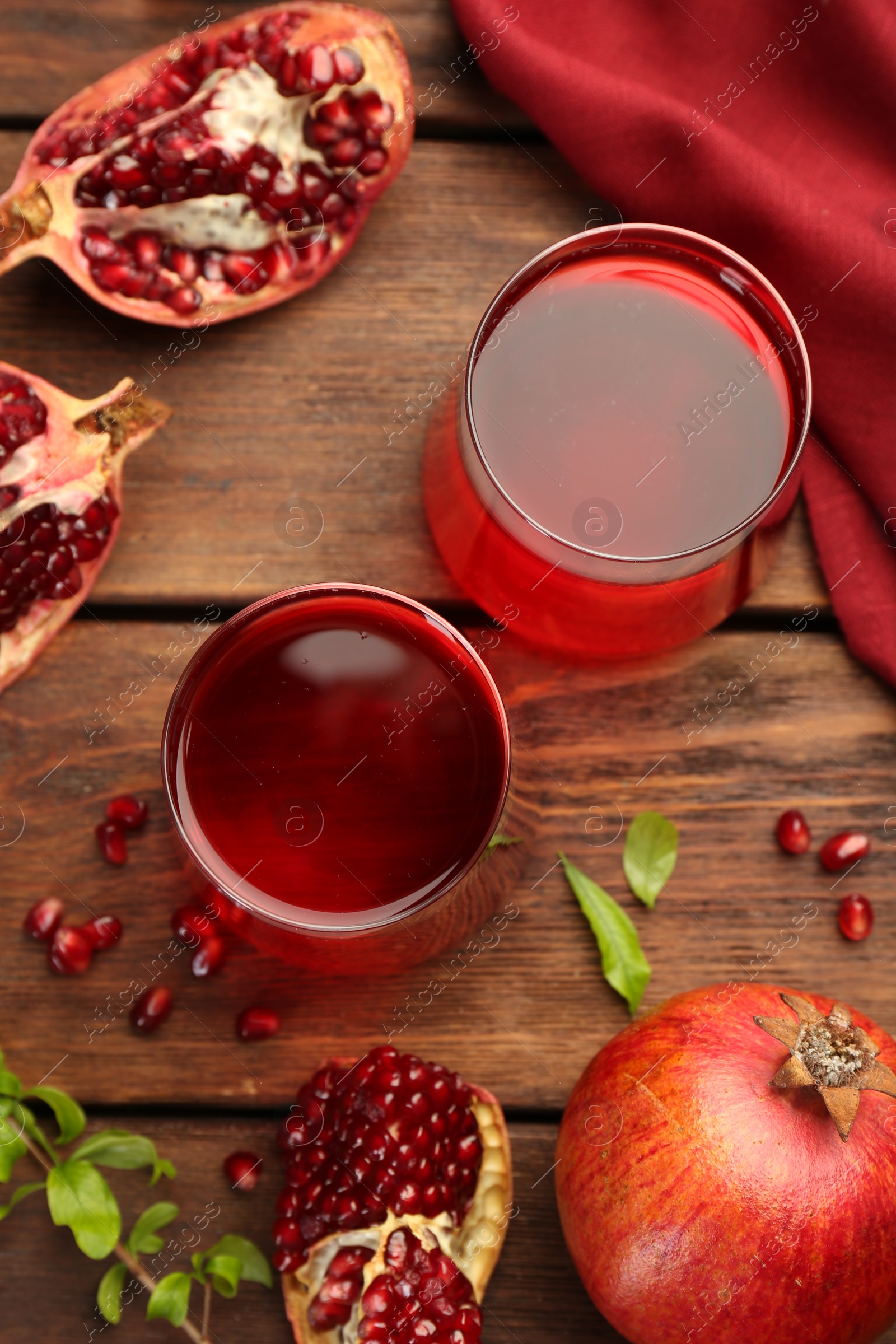Photo of Tasty pomegranate juice in glasses and fresh fruits on wooden table, flat lay