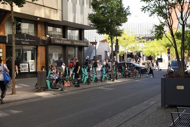 Photo of Cologne, Germany - August 28, 2022: View of city street with people and parked electric scooters