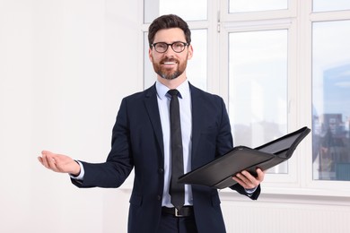 Photo of Handsome real estate agent with documents indoors
