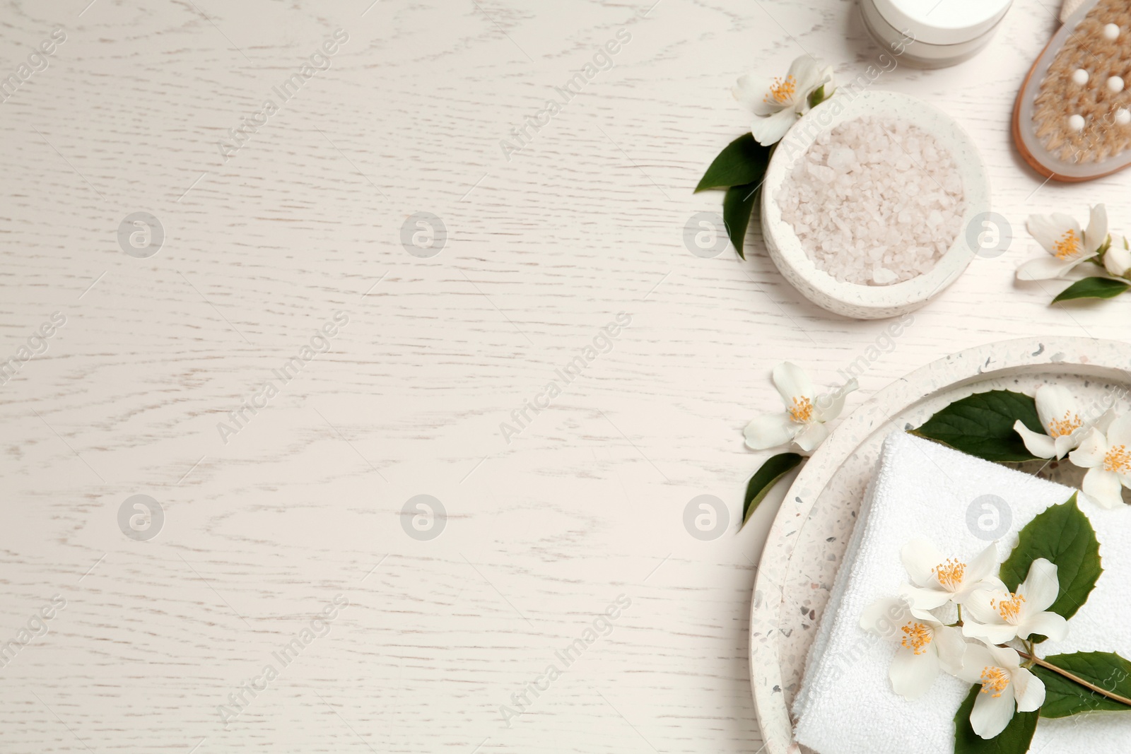 Photo of Flat lay composition with sea salt and beautiful jasmine flowers on white wooden table, space for text