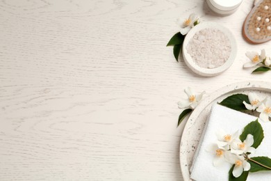 Photo of Flat lay composition with sea salt and beautiful jasmine flowers on white wooden table, space for text