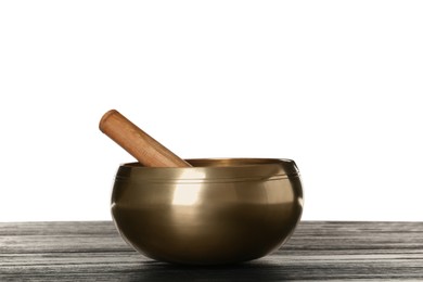 Golden singing bowl and mallet on wooden table against white background