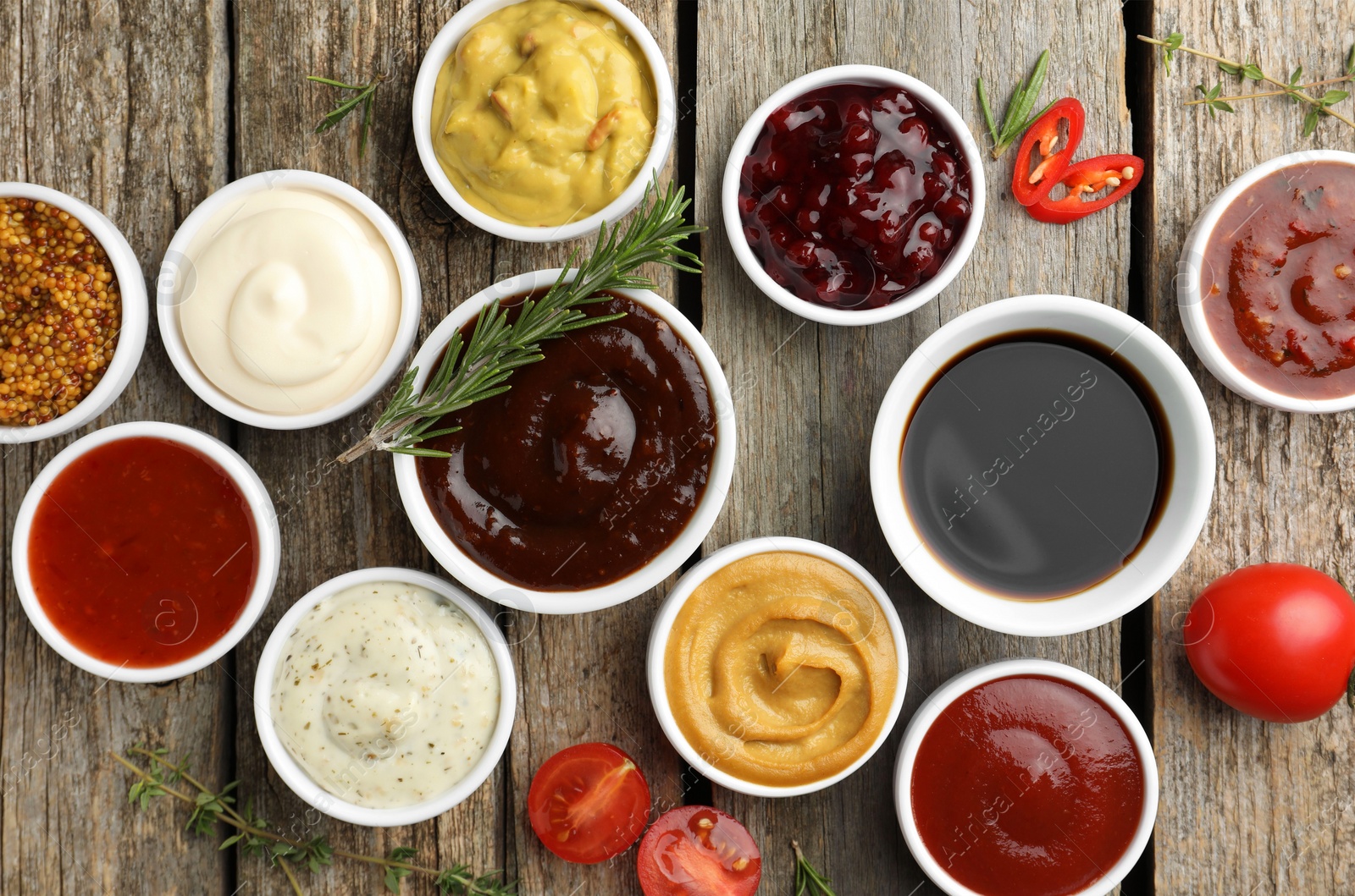 Photo of Different tasty sauces in bowls and ingredients on wooden table, flat lay