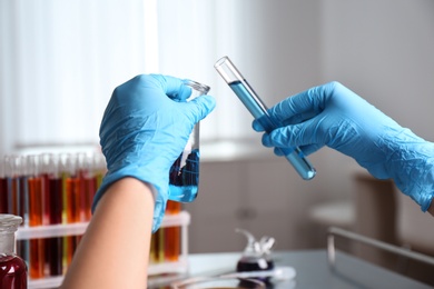 Scientist holding tube and conical flask at laboratory, closeup. Solution chemistry