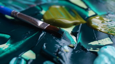 Photo of Brush on artist's palette with mixed paints, closeup