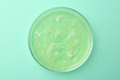 Petri dish with color liquid sample on light blue background, top view