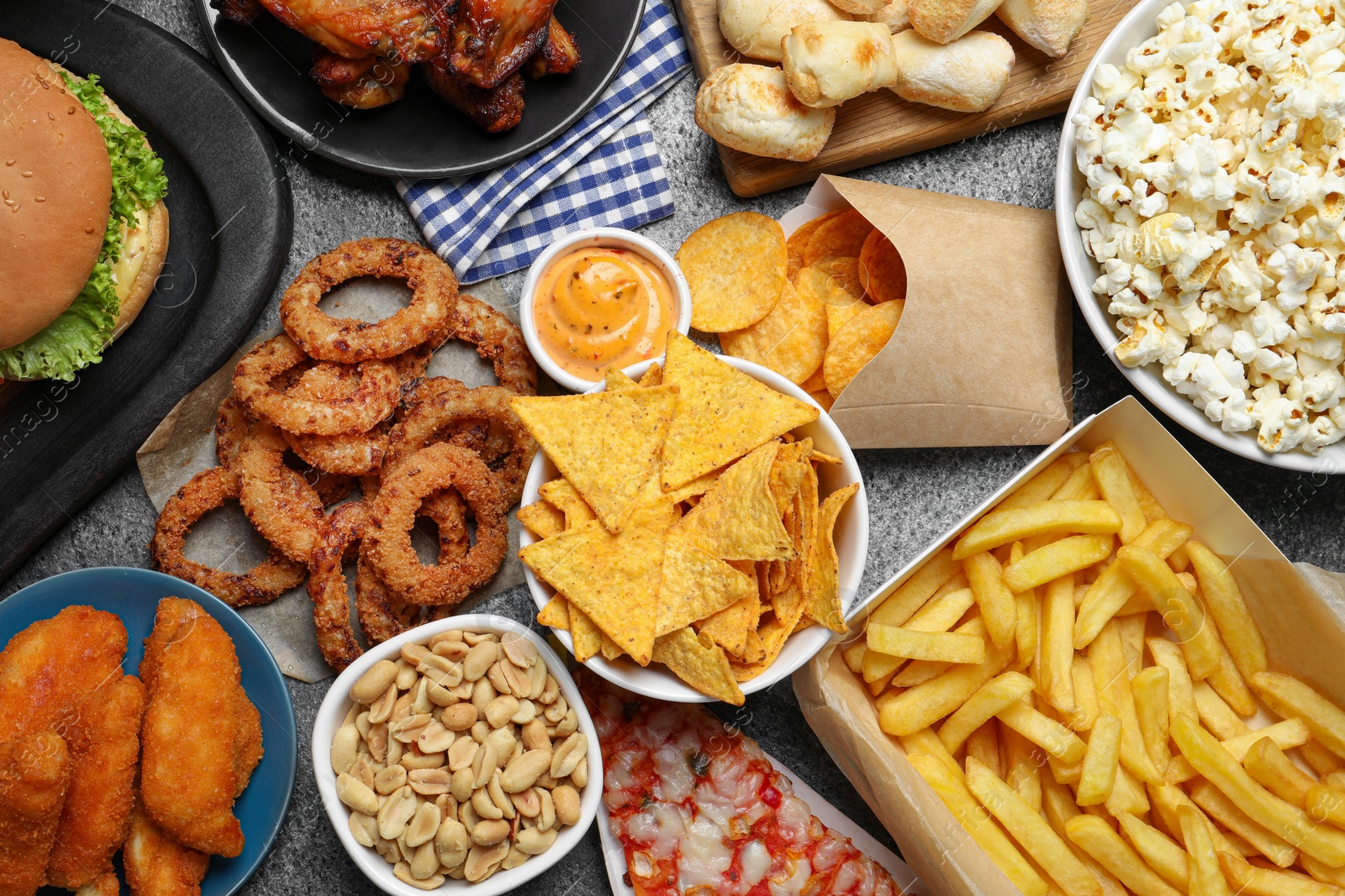 Photo of French fries, burger and other fast food on gray table, flat lay