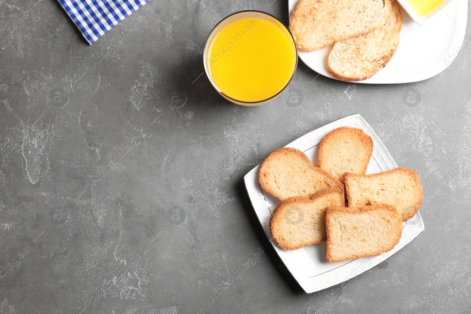 Photo of Plate with toasted bread and glass of juice on grey background, top view