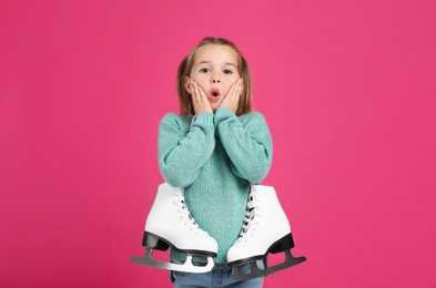 Photo of Excited little girl in turquoise knitted sweater with skates on pink background