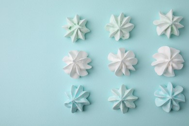 Photo of Delicious meringue cookies on light blue background, flat lay. Space for text