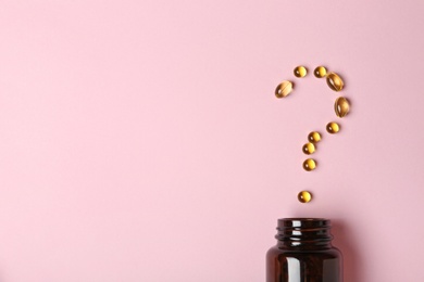 Photo of Question mark of cod liver oil capsules and jar on color background, flat lay. Space for text