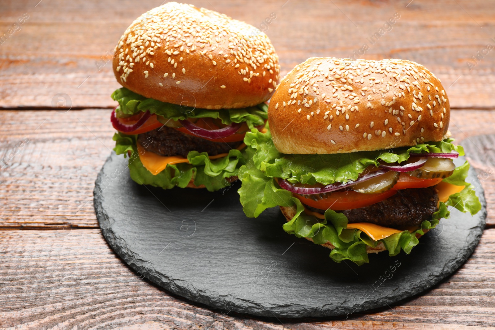 Photo of Tasty burgers with patties and vegetables on wooden table. Fast food