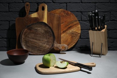 Photo of Wooden cutting boards, cut apple and knives on gray table