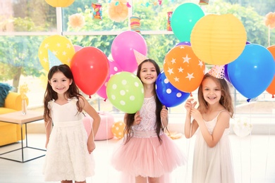 Cute girls with balloons at birthday party indoors