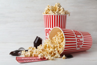 Photo of Popcorn, tickets and film footage on white wooden table. Cinema snack