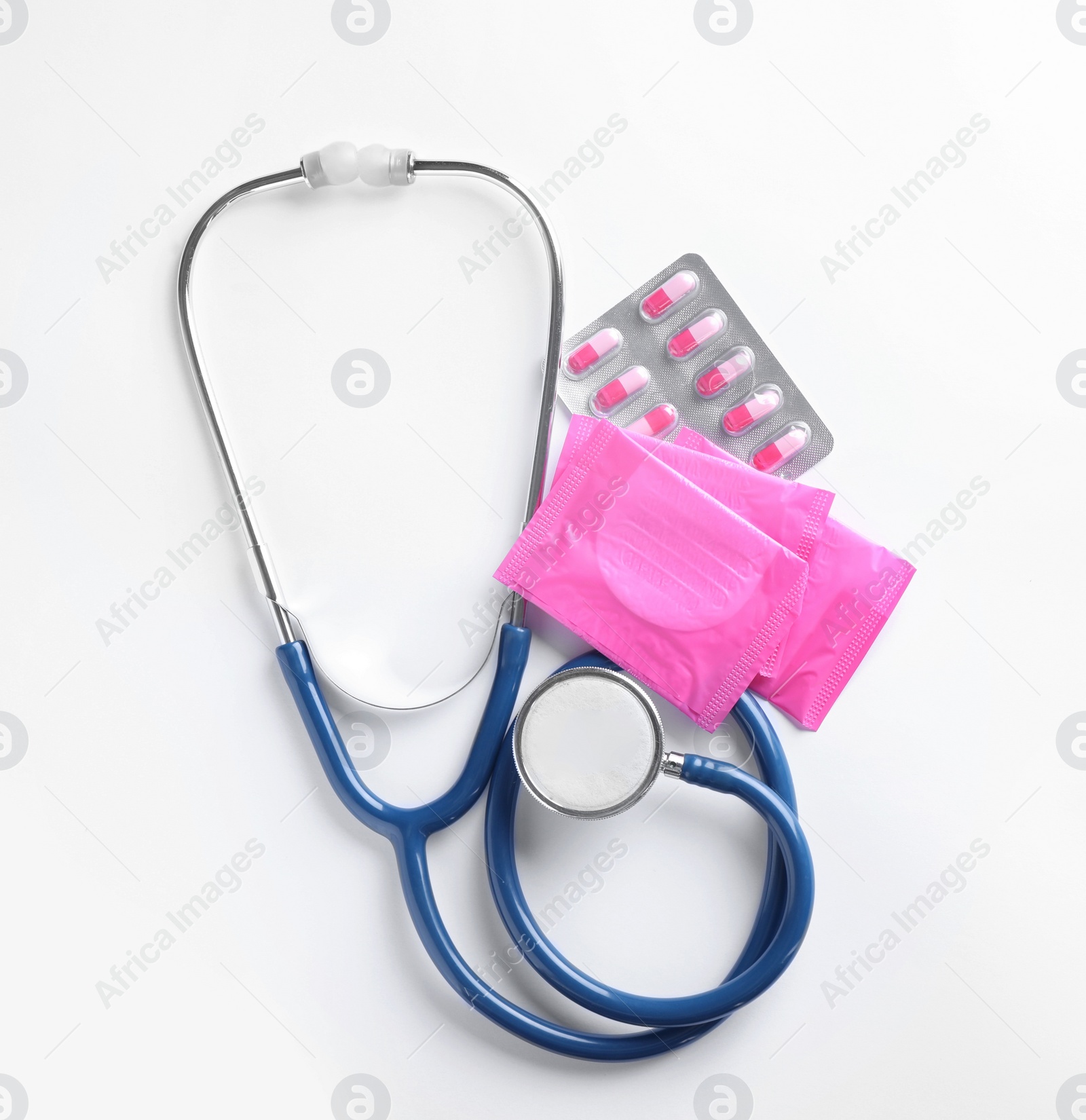 Photo of Stethoscope, menstrual pads and pills on white background, top view. Gynecology concept