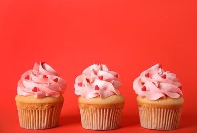 Photo of Row of tasty cupcakes on red background, space for text. Valentine's Day celebration