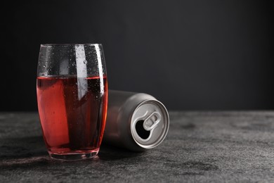 Photo of Energy drink in glass and aluminium can on grey table. Space for text