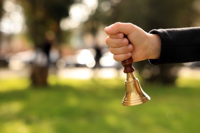 Photo of Pupil holding school bell outdoors on sunny day, closeup. Space for text