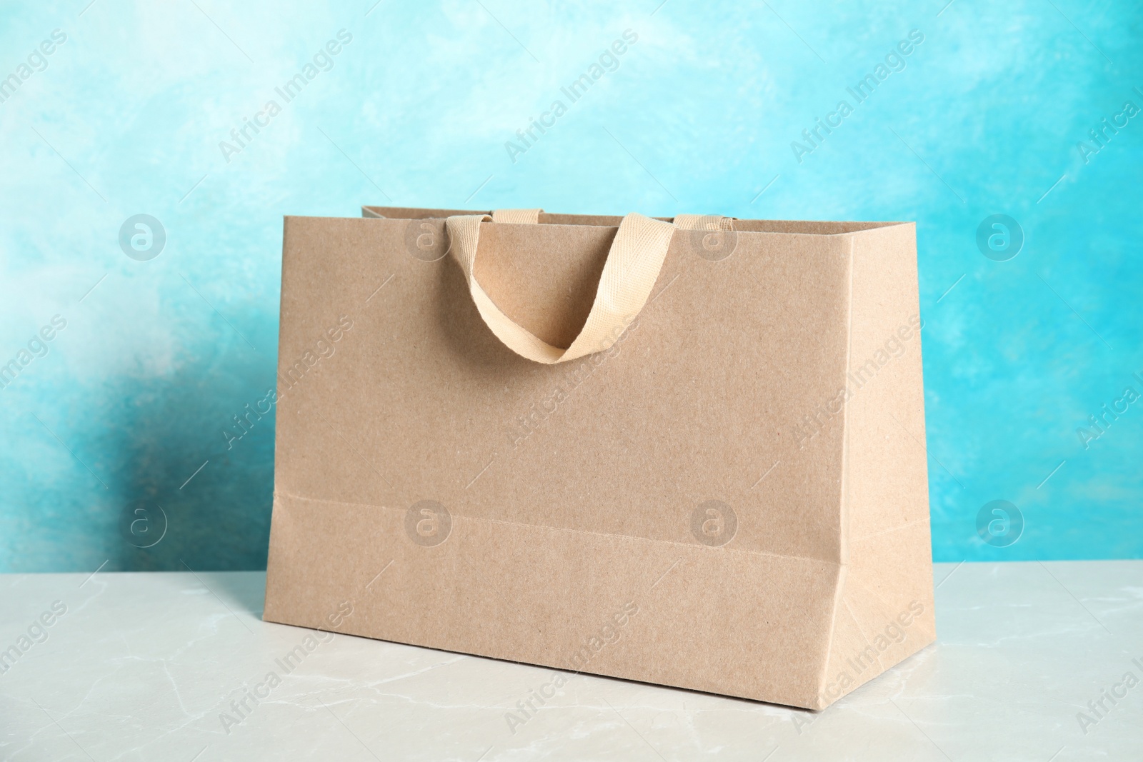 Photo of Paper shopping bag on table against color background. Mock up for design