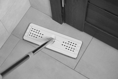 Cleaning grey tiled floor with mop, above view