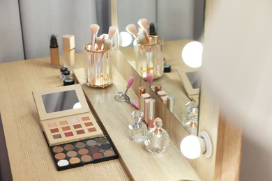 Photo of Different beauty products and perfumes on wooden dressing table in room