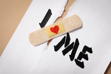 Photo of Torn paper with phrase I Love Me and sticking plaster, closeup