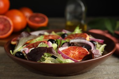 Photo of Bowl of delicious sicilian orange salad on wooden table, closeup