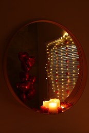 Photo of Mirror and burning candles in bathroom decorated for Valentine's day