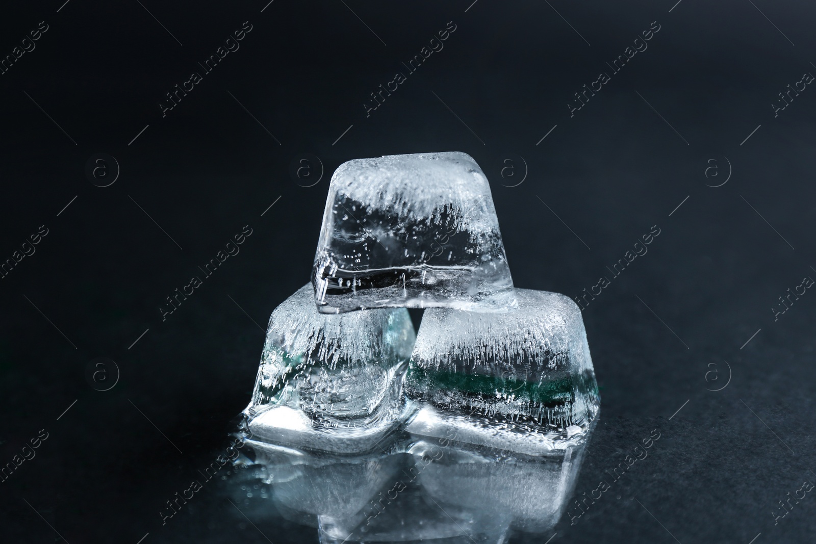 Photo of Ice cubes on wet black surface, closeup