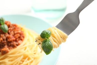 Fork with delicious pasta over plate, closeup