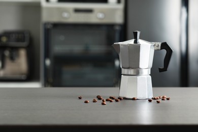 Photo of Moka pot and coffee beans on grey table in kitchen. Space for text