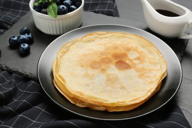 Delicious crepes with mint and blueberries on grey table