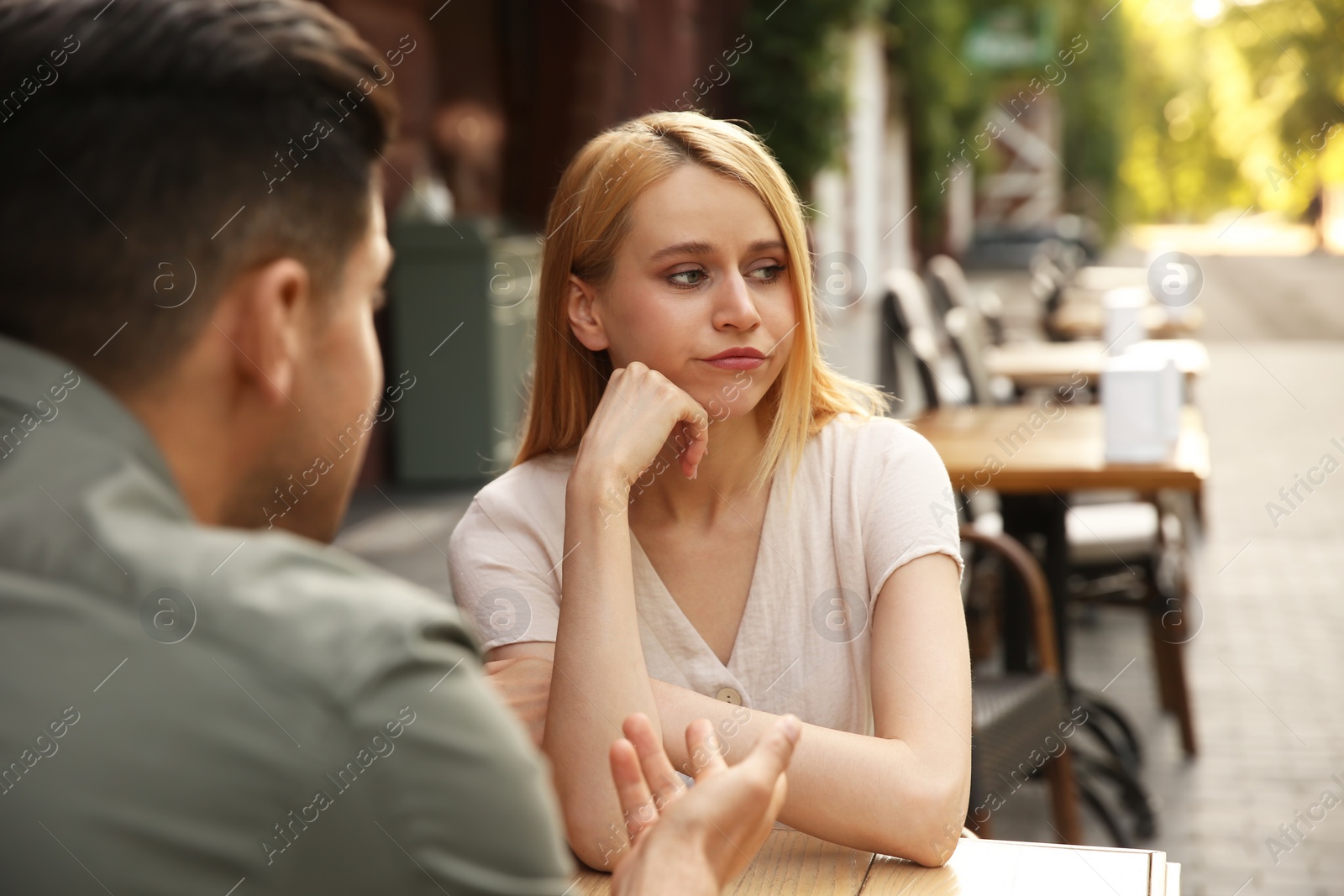 Photo of Young woman getting bored during first date with man at outdoor cafe