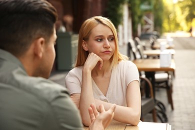 Young woman getting bored during first date with man at outdoor cafe